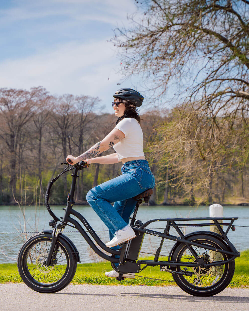 Rider on MOD CarGo 3 e-bike with extended Snap-On rack, showcasing versatile design by a scenic lake.