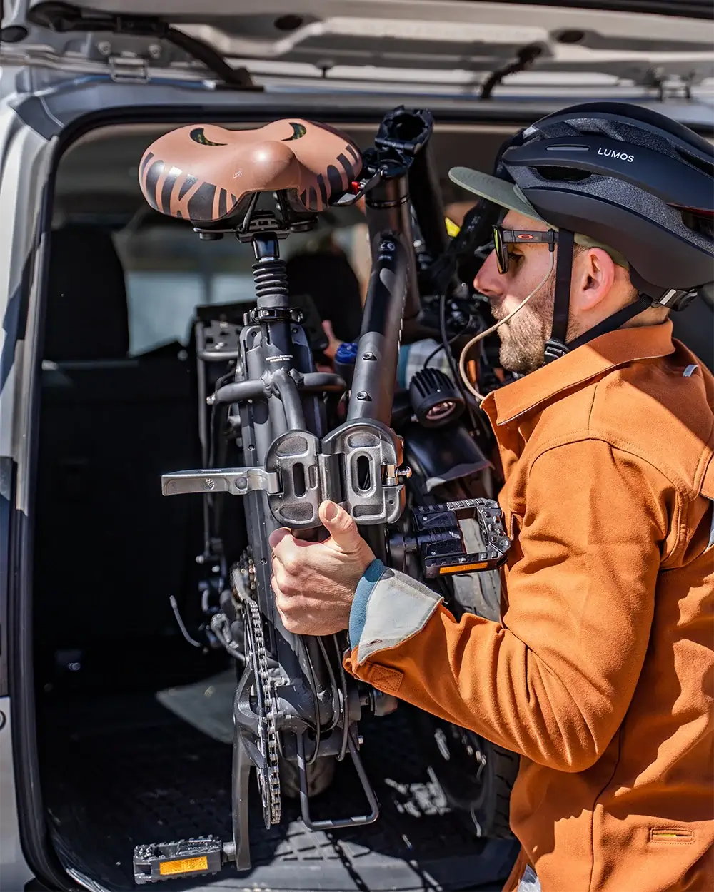 Man loading the MOD City+ foldable electric bike into the trunk of a vehicle for easy transport.