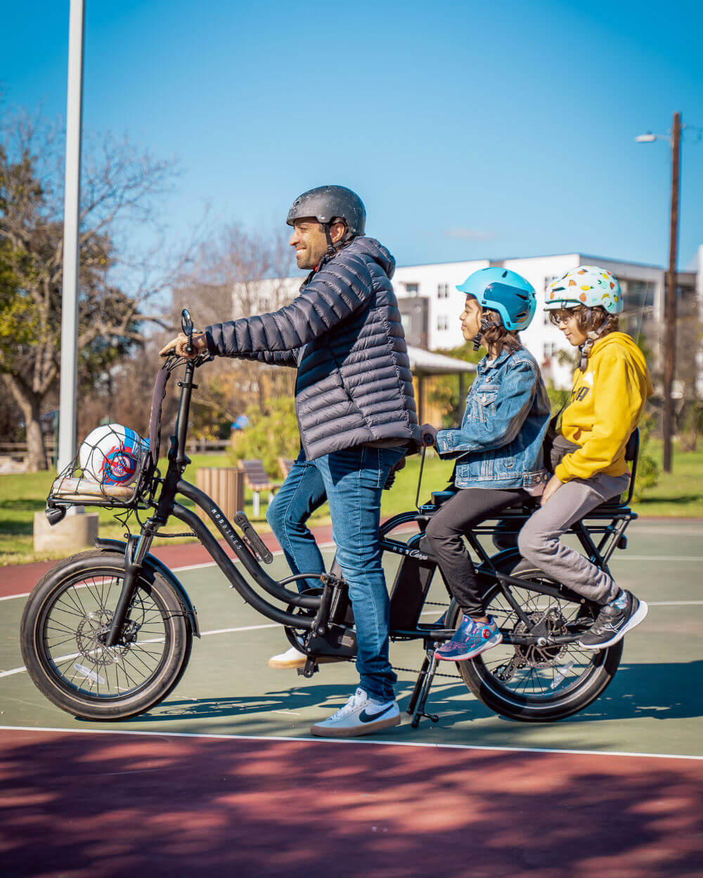 Two children and an adult riding the versatile MOD CarGo 3 bike with Snap-On rack, showcasing its sturdy design and passenger capacity.