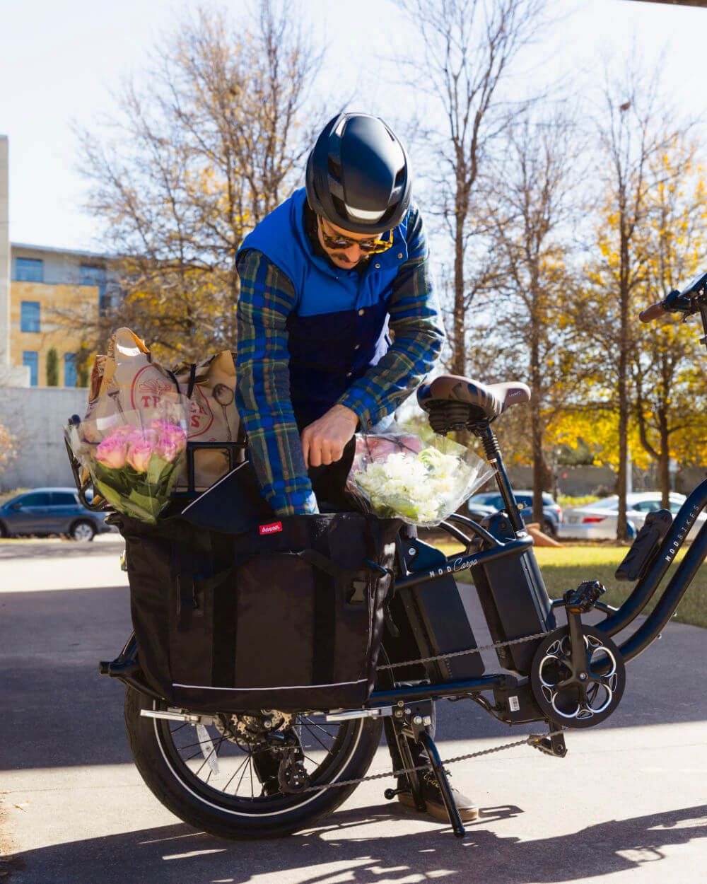 Person using MOD CarGo 3 bike with Snap-On rack for transporting flowers and bags on a sunny day.