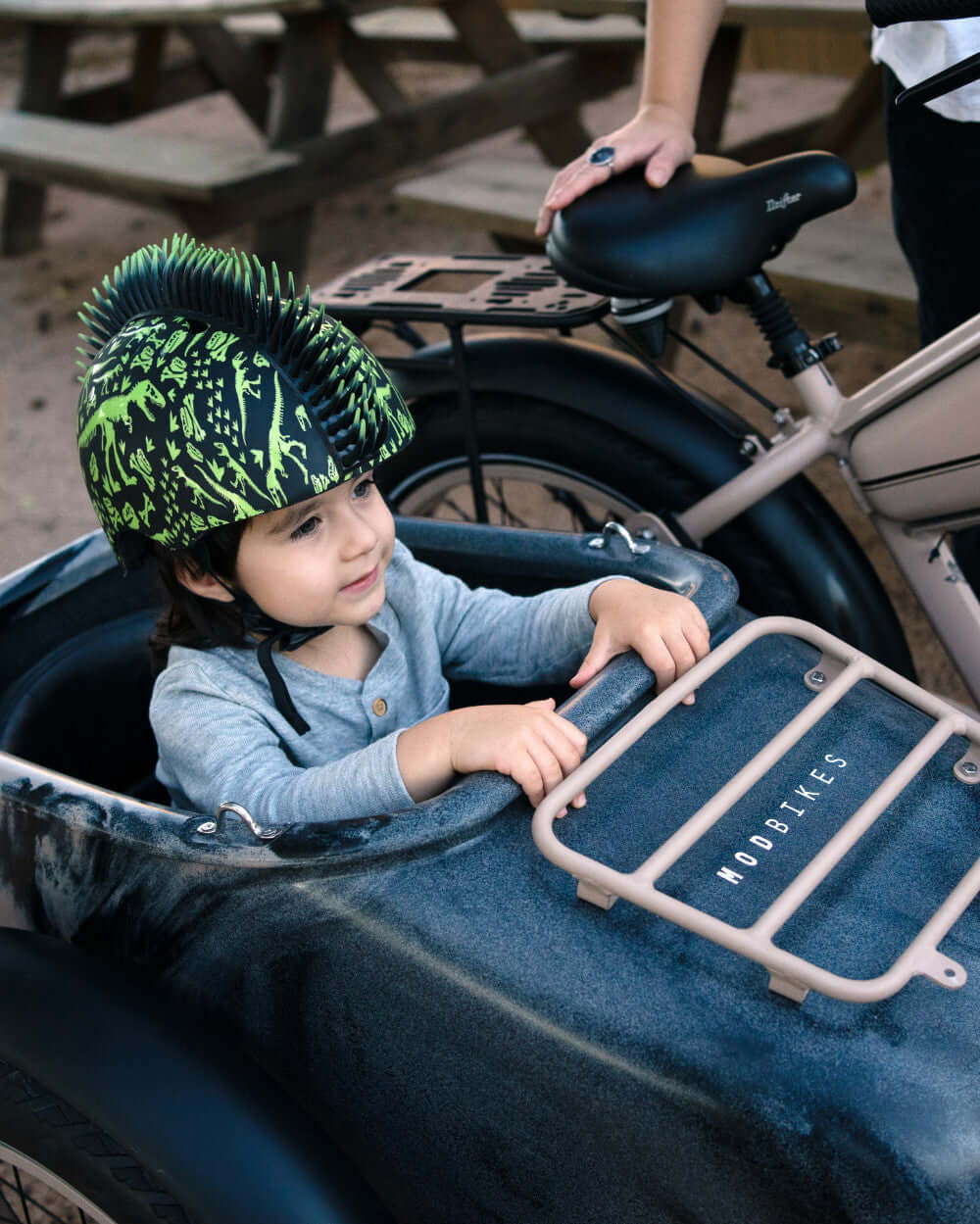 Child wearing a spiked helmet sitting in the MOD Easy SideCar Sahara, enjoying a ride outdoors.